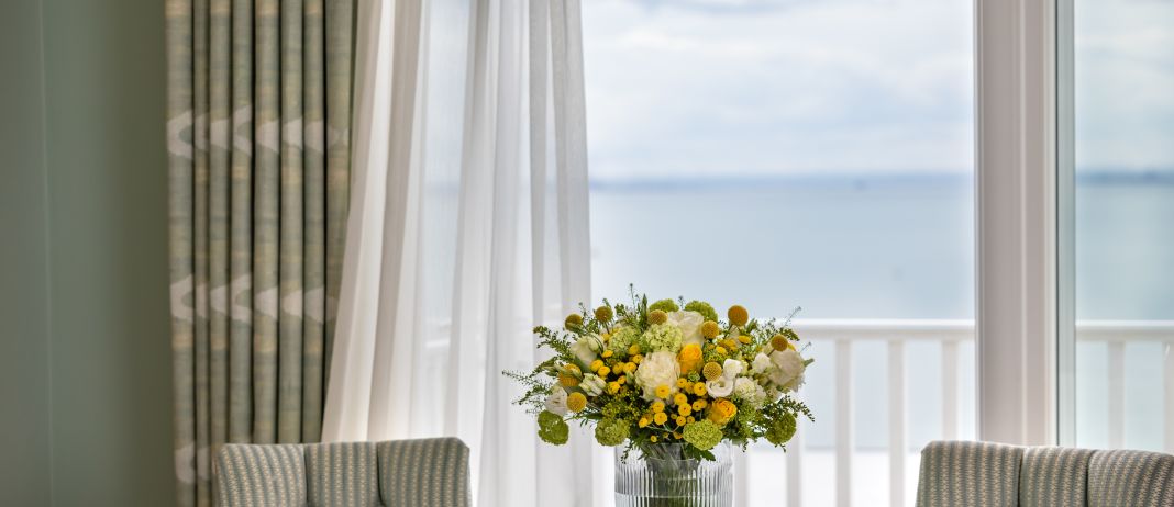 A Vase Of Flowers Sits In Front Of A Window